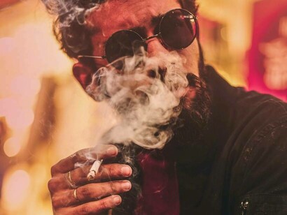 A man exhales a cloud of smoke after taking a puff from his cigarette