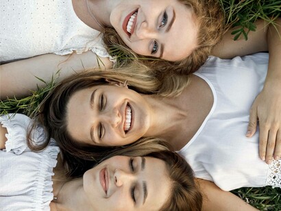 Three friends laying down on the grass and smiling to indicate that their friendship is surely not fake