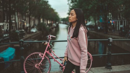 A woman in a hoodie standing on a footbridge in Amsterdam, Netherlands