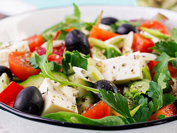 A Greek salad featuring cucumber, tomato, sweet pepper, lettuce, green onion, feta cheese, and olives, all drizzled with olive oil – a vibrant, nutrient-packed dish that supports brain health and embodies the principles of the Mediterranean diet
