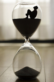 An hourglass resting on the floor, time slipping away, a poignant symbol of life's transience