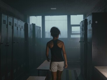 A female athlete in a professional locker room, surrounded by empty benches under dramatic, low lighting