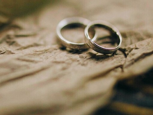 Wedding rings lie side by side, symbolising the social expectations that can surround marriage and family honour