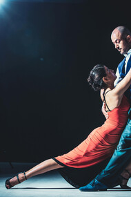 A couple tangoing beneath the spotlight