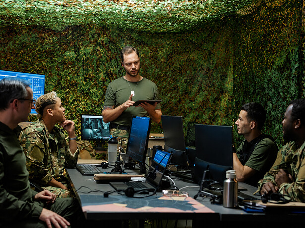 Young officer reviewing operational data on a tablet during a military strategy meeting