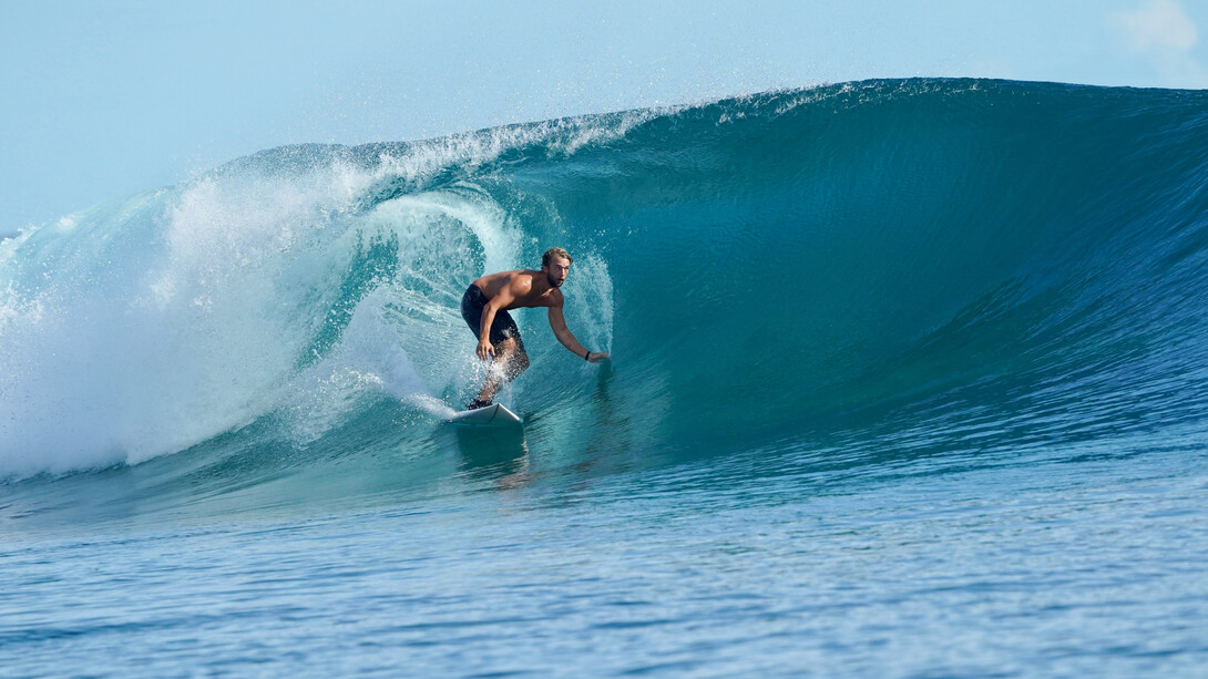 À l’aube, planches sous le bras et regard tourné vers l’horizon, les surfeurs incarnent cette quête inlassable des conditions parfaites qui rythme la culture de la glisse