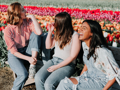 Three friends laughing together while surrounded by a field of tulips