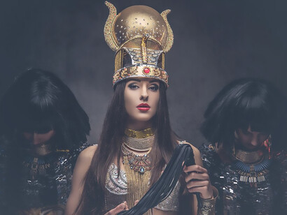 Portrait of haughty egyptian queen in an ancient pharaoh costume with two concubines