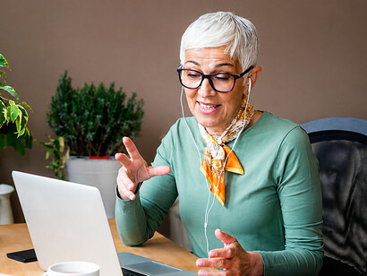 A mature woman working from home during an online meeting in a modern home office