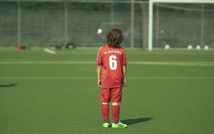 “A faceless teenage football player standing on the field