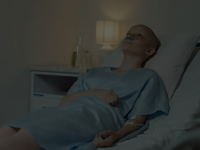 In the quiet confines of a hospital room, a woman grappling with cancer reclines in bed, draped in a hospital gown, navigating the challenges of chemotherapy with quiet strength and determination