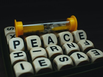 An hourglass lying over the word "peace," symbolizing that peace is a decision made with every passing moment