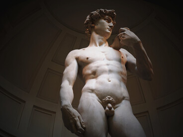 A dramatic low-angle view of Michelangelo’s iconic David inside the Accademia Gallery in Florence, Italy