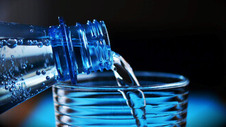 Clear glass and a water bottle with a mesmerizing visual as water gracefully flows from the bottle into the waiting glass