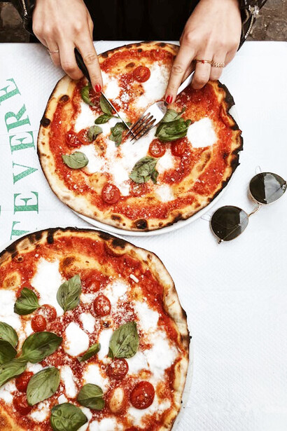 A person slicing a pizza in Rome, Italy
