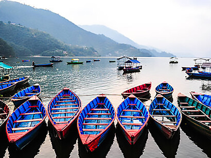 Colorful boats resting on Phewa Lake in Nepal, a serene freshwater lake in the Pokhara Valley surrounded by the city and nearby hills