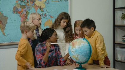 Professora demonstra a localização de país no globo terrestre. Os professores brasileiros se veem submetidos a jornadas extensas, que incluem a preparação de aulas, correção de atividades, planejamento burocrático e, muitas vezes, a condução de atividades adaptadas para alunos com necessidades especiais. Em escolas frequentemente superlotadas, a exigência de cumprir metas educacionais coloca a qualidade do ensino em segundo plano, agravando o estresse e contribuindo para a exaustão de muitos profissionais. Casos extremos, como de professoras que chegaram ao limite de sua resistência emocional e até faleceram em sala de aula, ilustram a gravidade dessa sobrecarga