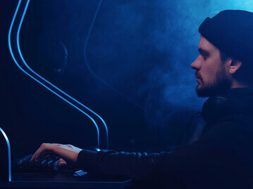 A man sits at his computer, confronting the harsh realities of social media harassment, online hate speech, cyberbullying, and the toxic digital environments that threaten personal dignity and well-being in the digital age