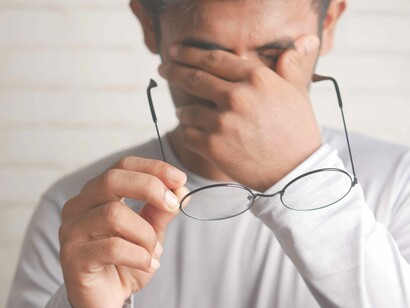 A tired man takes off his glasses to wipe his eyes as he contemplates existence during his mid mid-life crisis