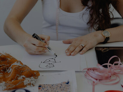 A woman sketching fashion designs, working as a clothing designer