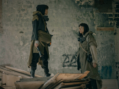 A man and a woman standing amid the remnants of a ruined world, representing the determination to endure even in the harshest realities