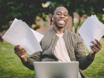 Exuding pure elation, a man joyfully releases papers into the air, capturing the essence of success, motivation, ambition, and the fulfillment of his goals