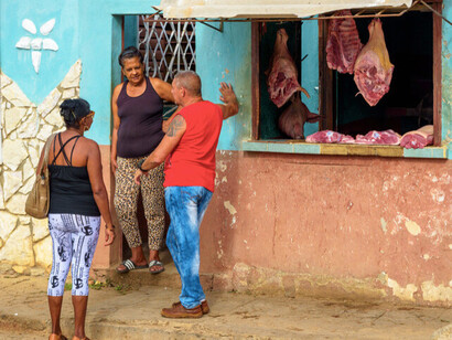 Locals stand outside the local butchery, exchanging stories and catching up, their laughter blending with the bustling sounds of the street