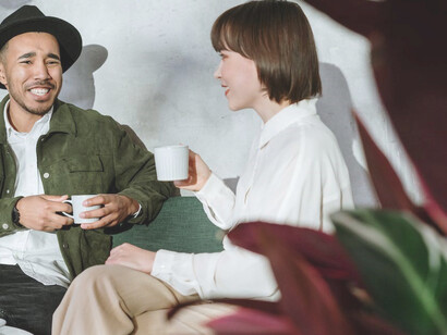 In another setting, a woman dressed in a white shirt and a man sporting a hat share a lighthearted speed date, relishing each moment