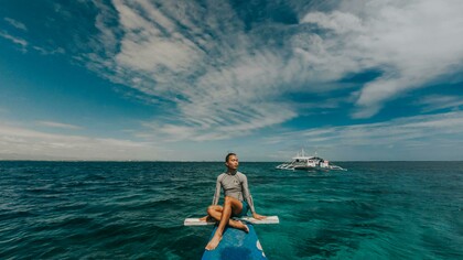 A woman wearing a rash guard in the sea in the Philippines, enjoying a peaceful travel moment