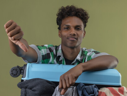 Young African American traveler holding a suitcase, passport, and visa documents at the airport