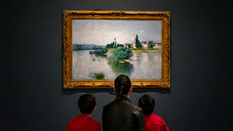 A woman in a black jacket sits on a red sofa with two children inside an art museum