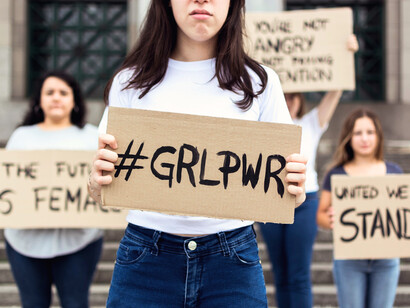 A group of young women raising their voices in a public space, symbolizing collective action and civic engagement