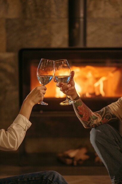 Wine glasses and food on a wooden table, set in a cozy fireside atmosphere