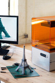 Impresora 3D junto a un modelo de la Torre Eiffel
