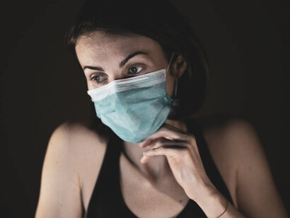 A masked woman during the pandemic, her expression heavy with sadness and depression