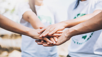 A close-up of volunteers forming a star shape with their hands, showcasing teamwork and unity