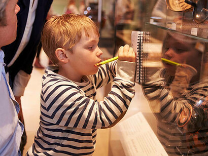 A family observes artifacts in a glass display during a museum visit, engaging with art education while fostering creative and emotional intelligence