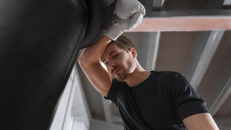 A tired and stressed man boxing, showing signs of frustration and struggle