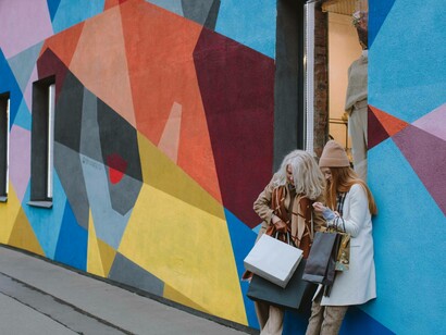 Grandmother and granddaughter leaning against a colorful wall