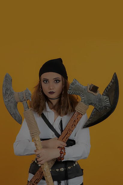 Pretty young pirate girl holding axes and looking at camera