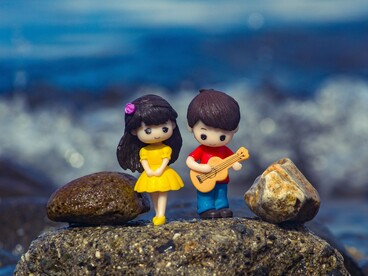 A pair of figurines sharing a simple moment together, representing that love is built through shared experiences rather than grand gestures