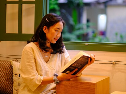 A woman absorbed in a book during a calm moment alone, reflecting a simple way to nurture personal well-being