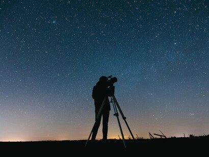 Pessoa observa céu estrelado com telescópio. Quando o empírico e o acadêmico se unem, eles transformam a produção de conhecimento em algo que é ao mesmo tempo prático, acessível e cientificamente robusto. Essa interação resulta em saberes aplicáveis, que não apenas resolvem problemas reais, mas também impulsionam o progresso em diferentes áreas do conhecimento humano