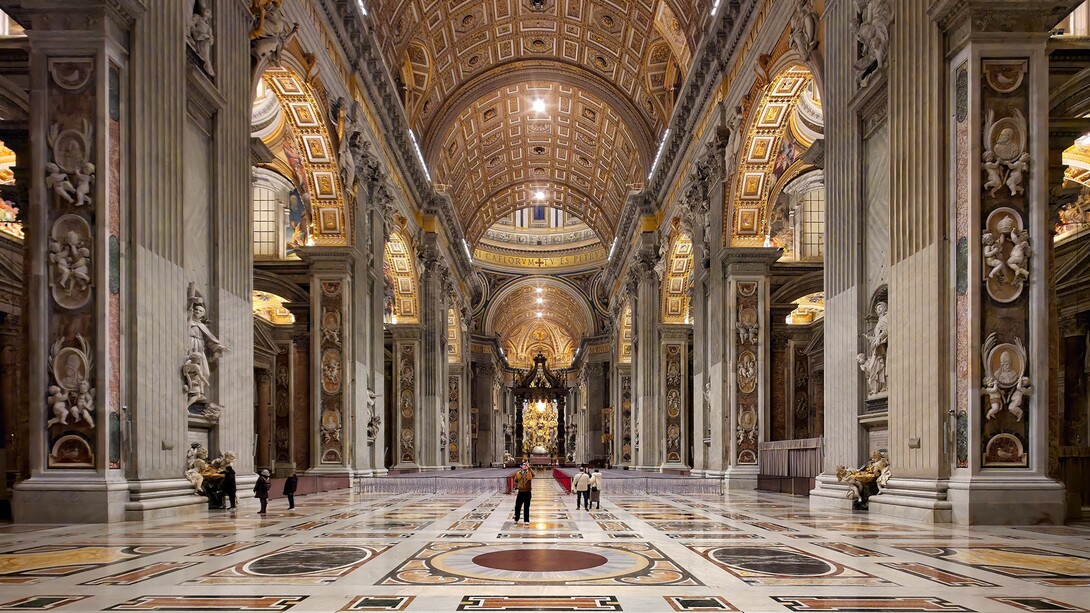 La navata centrale della Basilica di San Pietro si apre come un immenso spazio solenne e luminoso, scandito da colossali pilastri e ornato da marmi policromi e mosaici dorati, che guidano lo sguardo verso l’altare papale. Foto di Nate Bergin. Basilica di San Pietro, Città del Vaticano