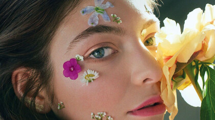A cantora Lorde iluminada pelo sol e beijada por pétalas de flores tropicais