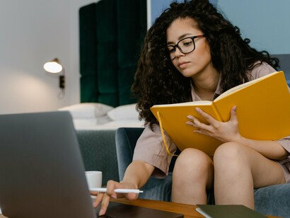 De óculos, uma mulher permanece concentrada diante do laptop enquanto acompanha o conteúdo exibido na tela. A leitura digital exige mais do que decifrar palavras: pressupõe atenção, seleção de informações e capacidade de avaliar criticamente aquilo que se encontra no ambiente virtual