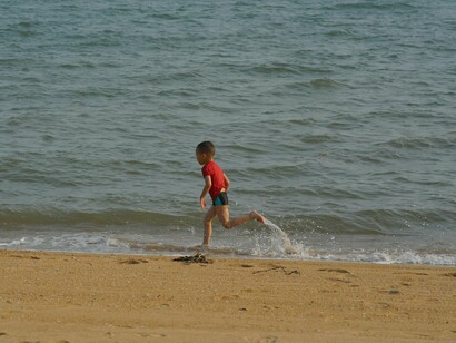 Menino correndo na beira do mar. Não sei por quanto tempo corri, mas de repente percebi que não estava mais perto da barraca de pipoca, nem da minha mãe, nem de ninguém que eu conhecia. Parei, ofegante, olhei ao redor e só vi rostos desconhecidos, uma multidão que não era mais familiar