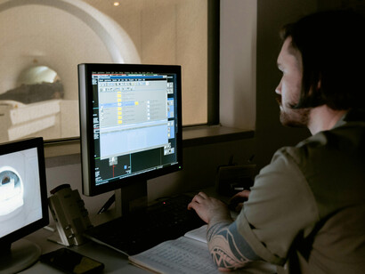 A medical professional observes brain imaging results on a monitor during an MRI scan