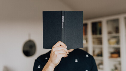 Autor esconde o rosto com o livro de sua história