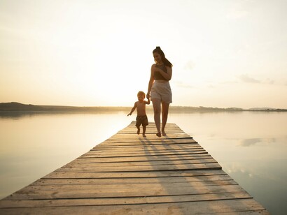 A woman and a child walking hand-in-hand on a dock towards a warm horizon beautifully symbolize the quiet moments of connection and the pursuit of inner serenity that can anchor the human spirit amidst life's complexities